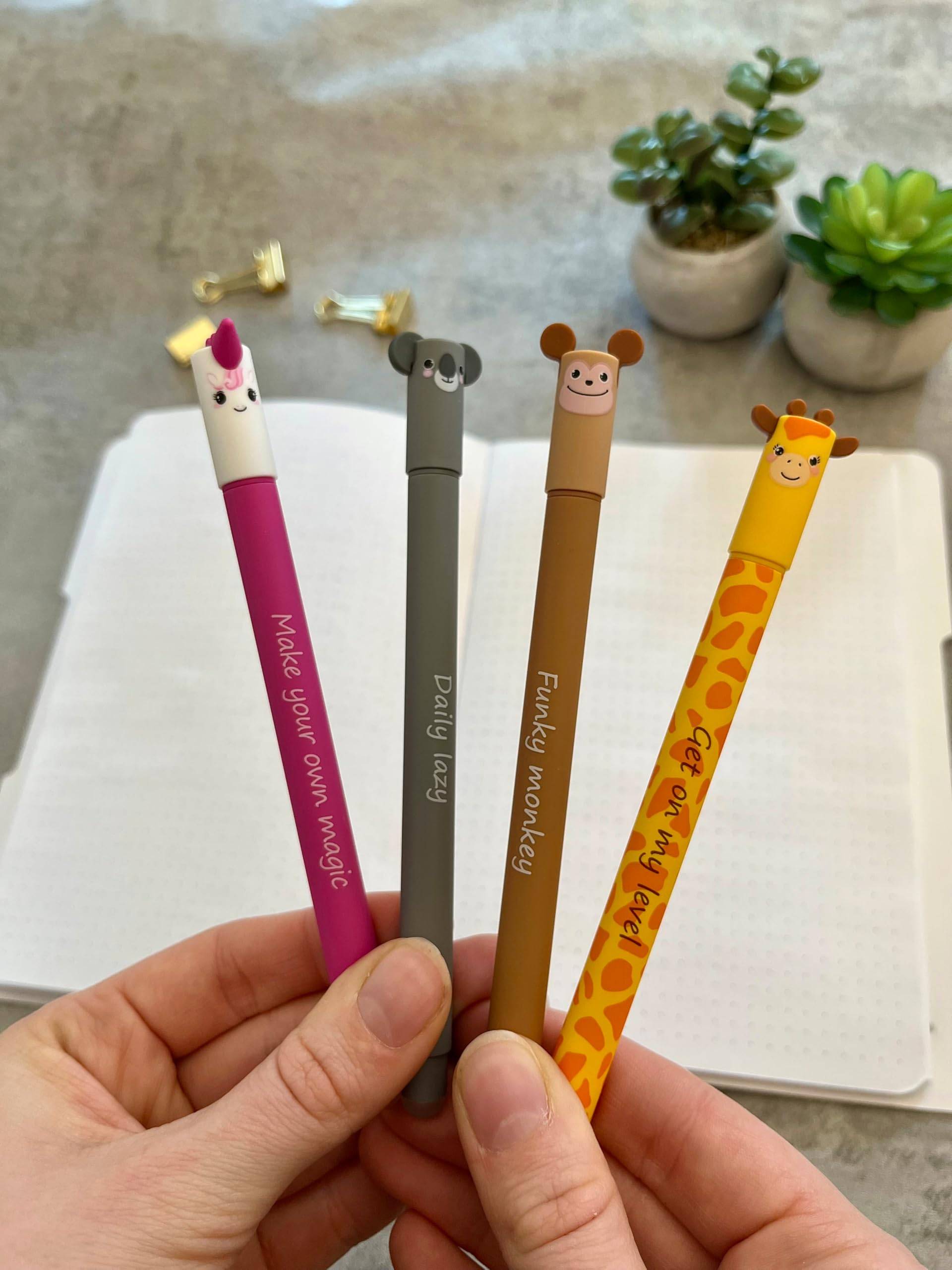 Hand hält vier tiergestaltige Stifte über einem offenen Notizbuch: Designs mit Einhorn, Koala, Affe und Giraffe mit motivierendem Text.