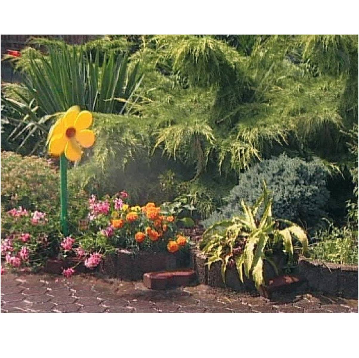 Ein Blumenbeet mit bunten Blumen und tropischen Pflanzen, mit einer großen gelben Windradblume auf einem grünen Stiel in der Nähe eines Ziegelpflasterweges.
