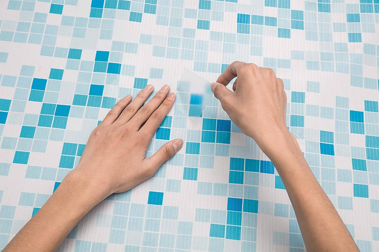 Hände bringen einen transparenten Klebeband auf eine blau-weiße Mosaikfliesenoberfläche auf.