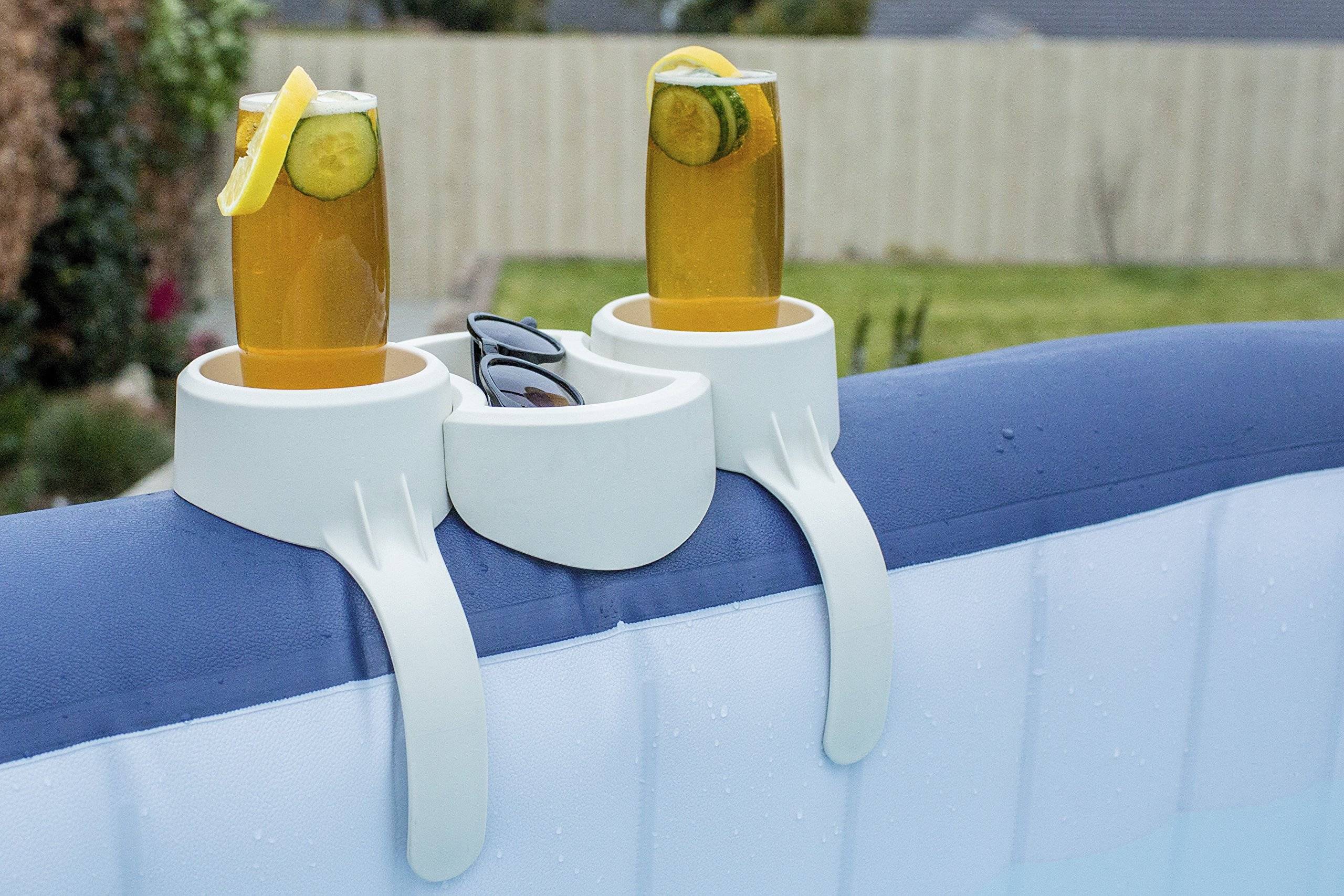 Zwei Gläser mit eisgekühlten bernsteinfarbenen Getränken mit Zitonen- und Limettengarnierung stehen in weißen Getränkehaltern, die an der Kante eines aufblasbaren Pools befestigt sind, mit einer Sonnenbrille dazwischen.