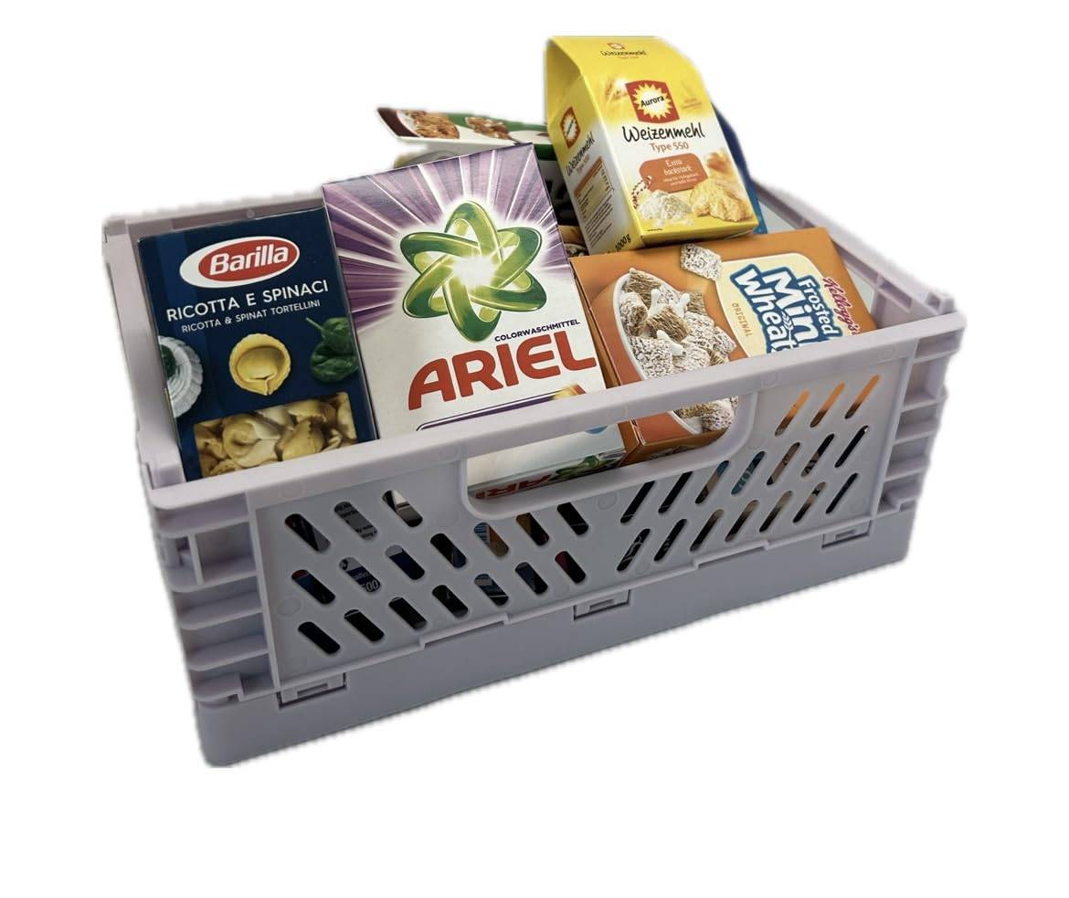 Ein graues Kunststoffkorb gefüllt mit verschiedenen Lebensmittel- und Haushaltsproduktkartons, darunter Ariel-Waschmittel, Pasta und Müsli, auf weißem Hintergrund.
