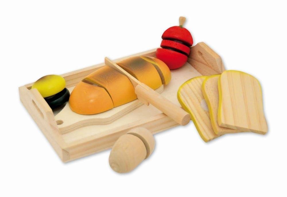 Holzspielzeug-Lebensmittelset auf einem Schneidebrett mit einem Messer, geschnittenem Laib, Brotstücken und einem rot-gelben Spielzeugartikel.