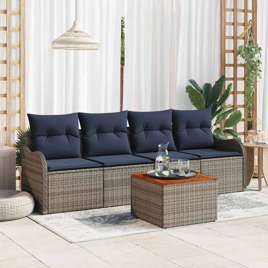 Outdoor-Terrassensitzgruppe mit Flechtsofa, marineblauen Kissen, passendem Ottoman-Tisch und Pflanzen in einem hellen, geschlossenen Verandabereich.