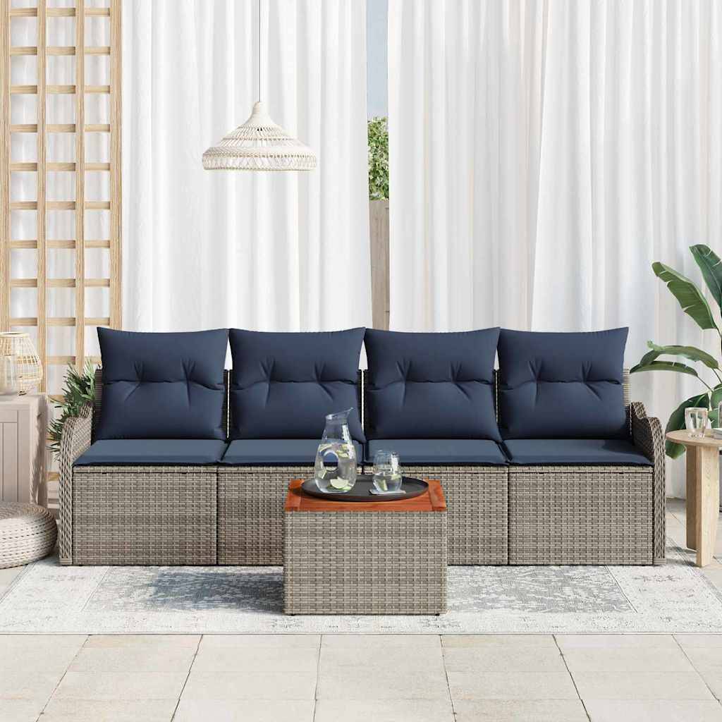 Gartenmöbel-Set für die Terrasse mit vier dunkelblau gepolsterten Stühlen, geflochtenen Rattanbasen und einem passenden quadratischen Couchtisch in einem hellen, modernen Raum.