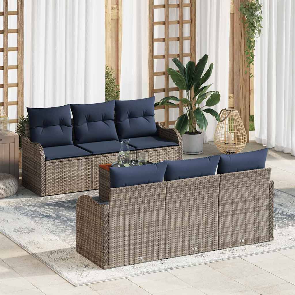 Sitzgarnitur für die Terrasse im Freien mit geflochtenen Rattanstil-Sofas, marineblauen Kissen, einem Tisch mit Glasplatte und Topfpflanzen auf einem hellen Teppich.