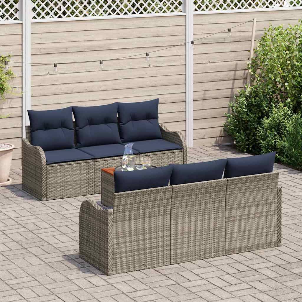 Außenbereich-Sitzgarnitur mit zwei geflochtenen Rattansofas und marineblauen Kissen auf einer gepflasterten Terrasse neben einem Zaun und einer Hecke.