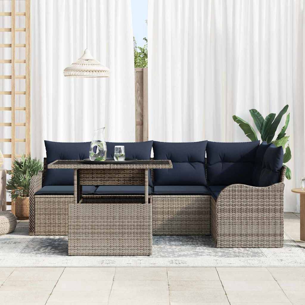 Gartensitzgruppe mit gewebtem Ecksofa, dunkelblauen Kissen, Couchtisch und Pflanzen vor weißen Vorhängen