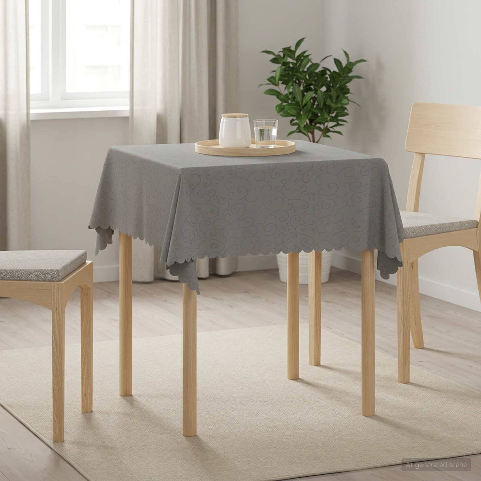 Kleiner Esstisch mit grauer Tischdecke, Tablett, Tasse und Glas neben einem Stuhl und Hocker in einem hellen, minimalistischen Raum.