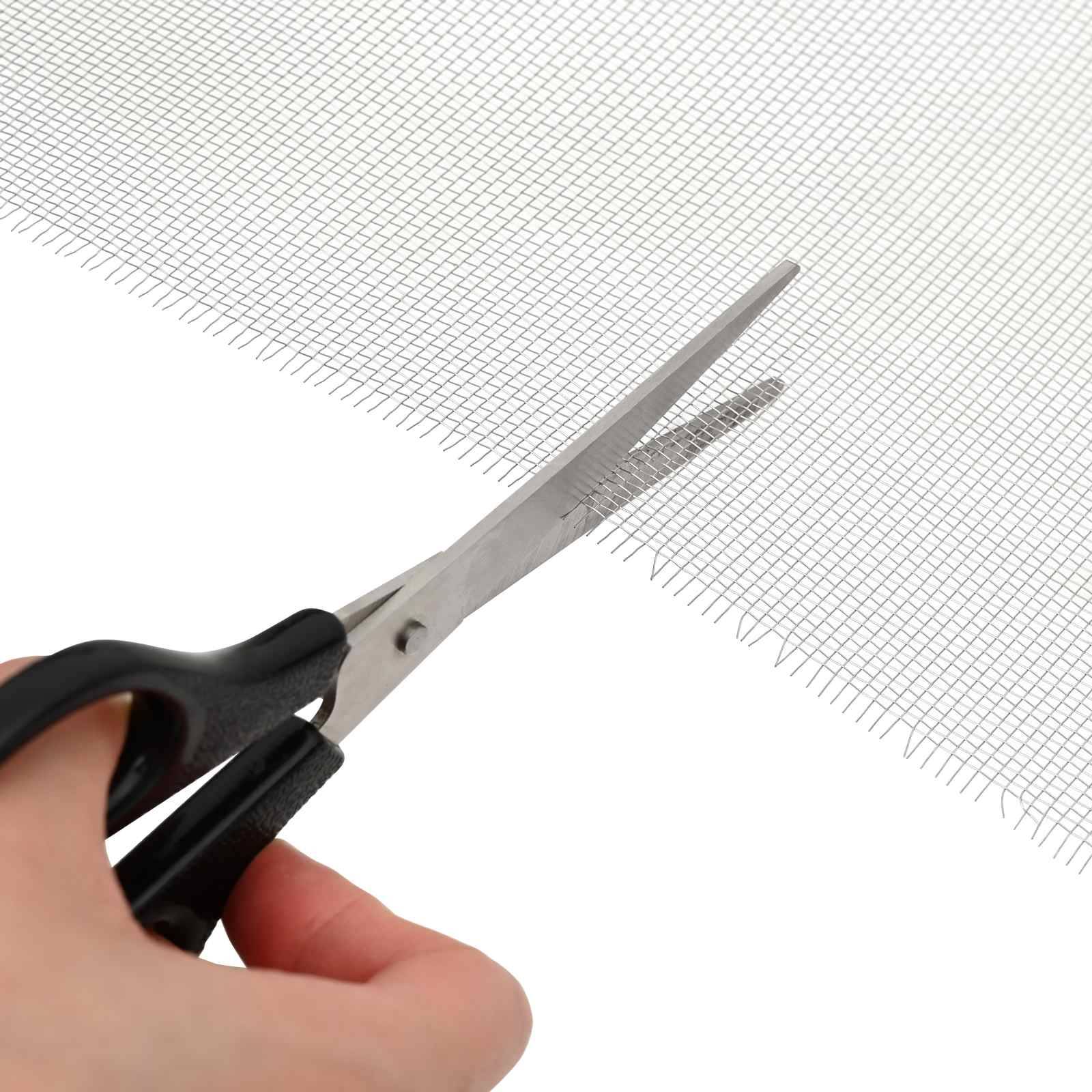 Eine Hand benutzt eine Schere, um ein Blatt feines Maschengewebe oder Siebstoff auf weißem Hintergrund zu schneiden.