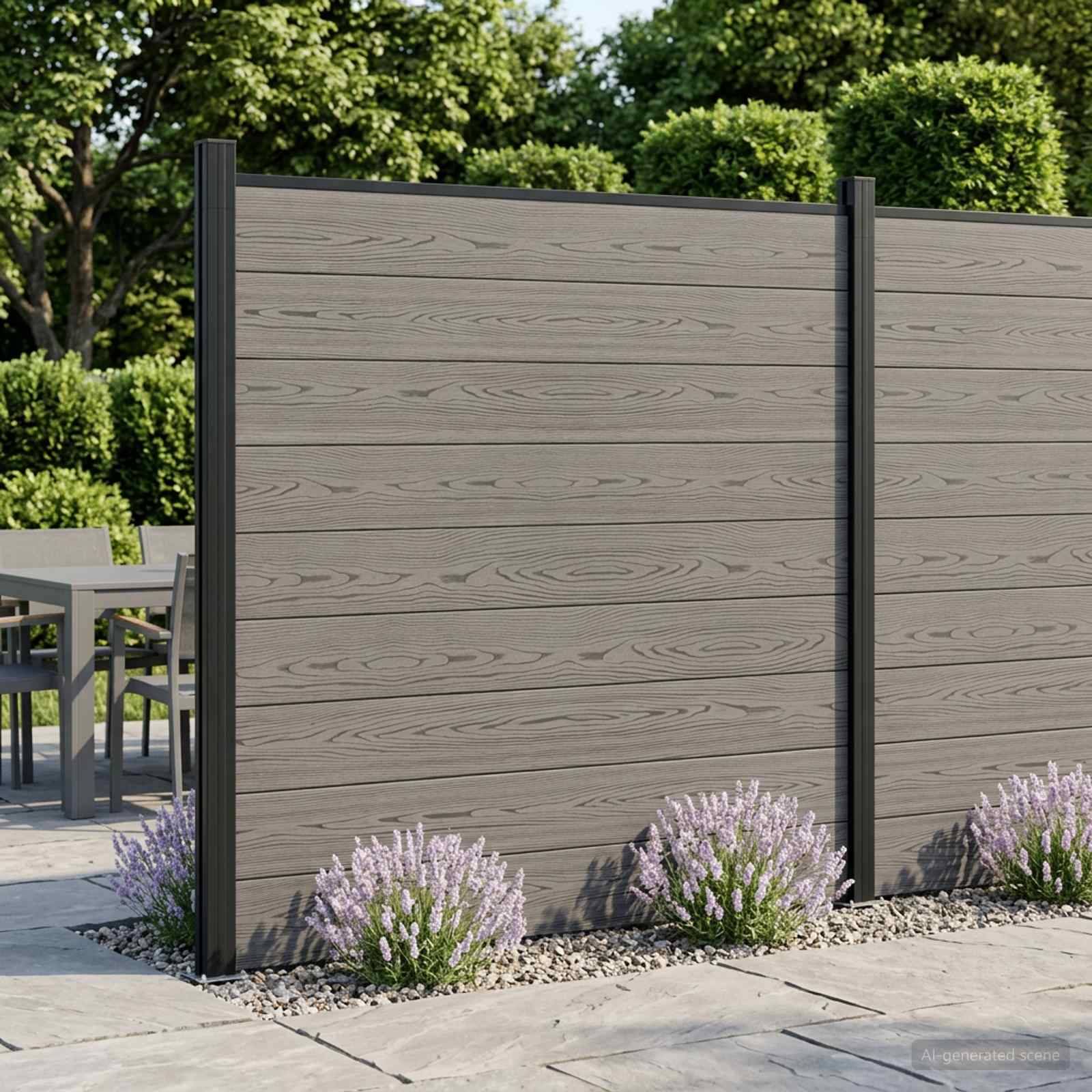 Außenzaun mit Sichtschutz aus grauem Holzoptik-Paneelen und schwarzen Pfosten neben einer Terrasse, mit kleinen Blütenpflanzen an der Basis.