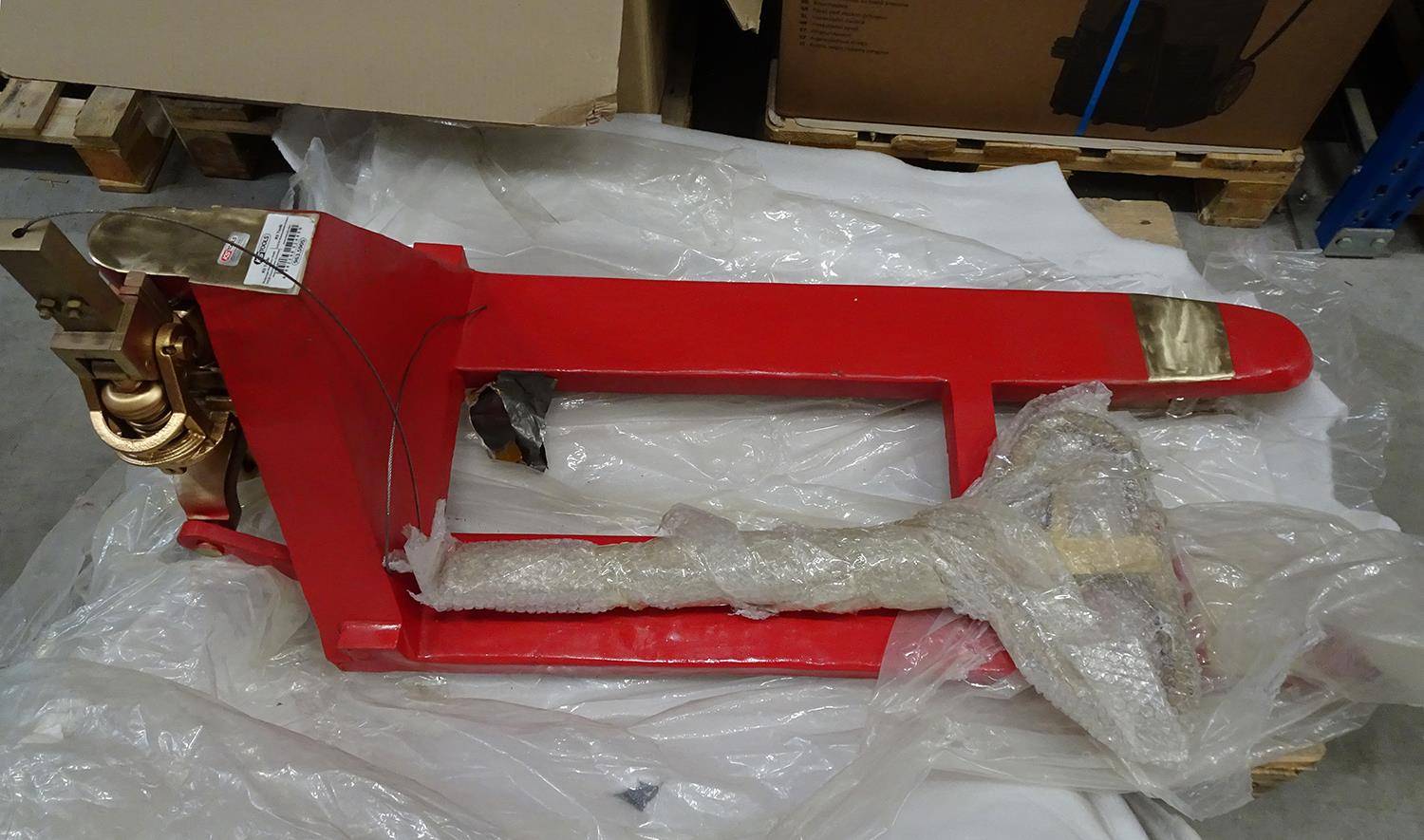 Rote industrielle Gabelaufsatz in Kunststoff eingewickelt, ruhend auf Verpackung in einem Lager- oder Lagerbereich.