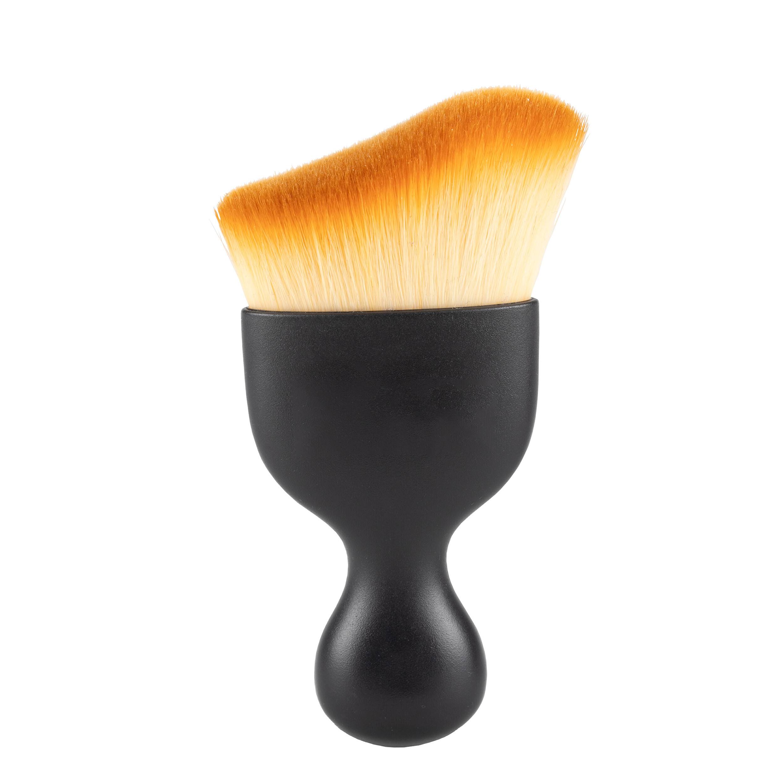 Schwarze Make-up-Bürste mit dichten, schräg angeordneten orangefarbenen Borsten auf weißem Hintergrund.