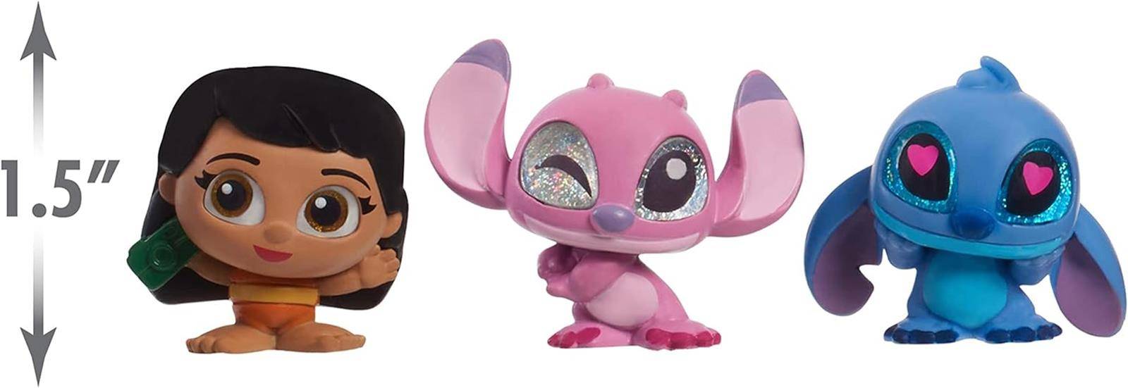 Drei kleine Spielzeugfiguren nebeneinander: eine braunhaarige Figur und rosa und blaue außerirdische Figuren mit einer Größenanzeige von 1,5 Zoll auf der linken Seite.