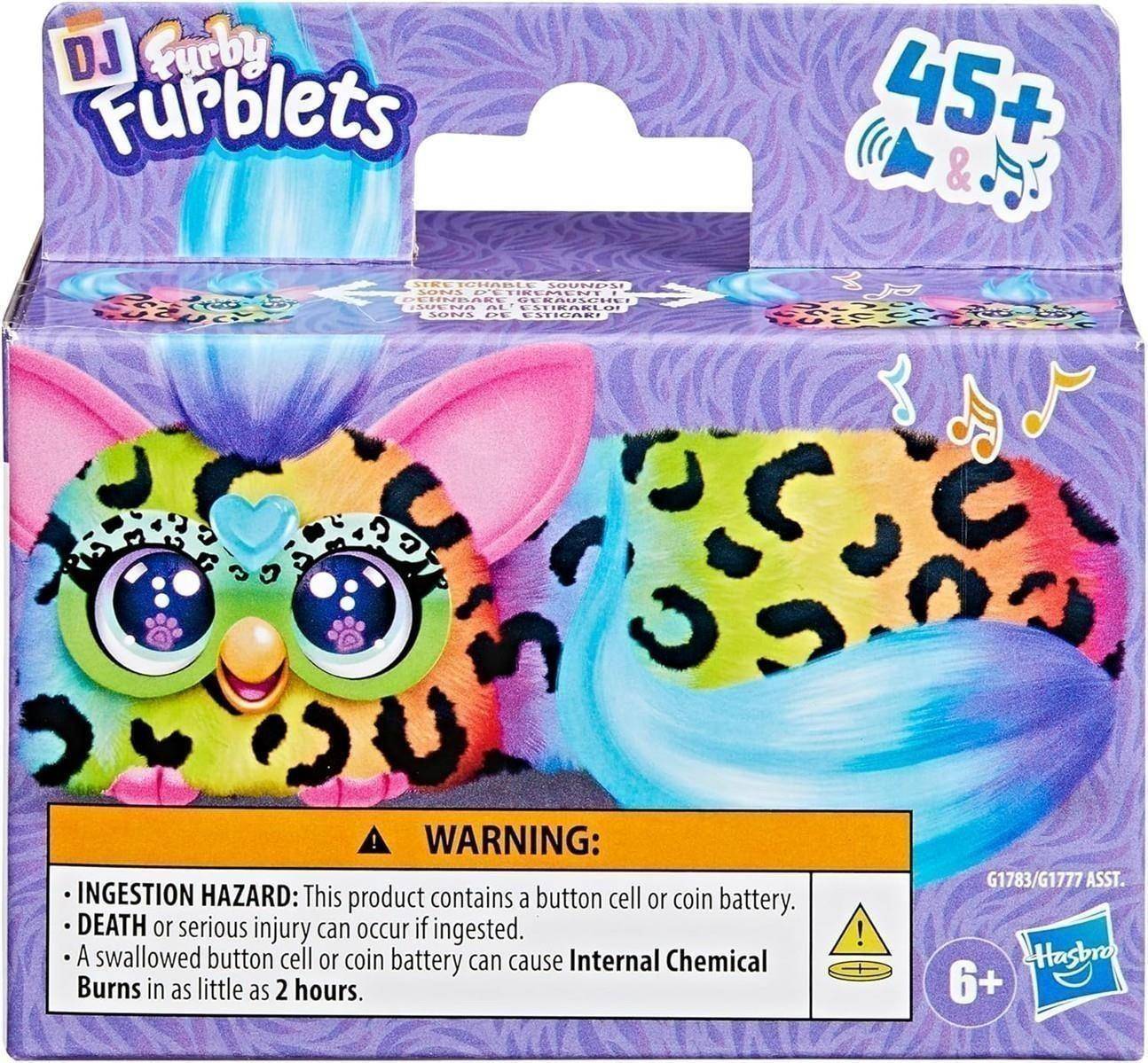 Packung eines DJ Furby Furblets Spielzeugs mit Leopardenmuster-Fell, großen Augen und Musiknoten, gekennzeichnet mit 45+ Sounds und 6+, mit Batteriewarnung.