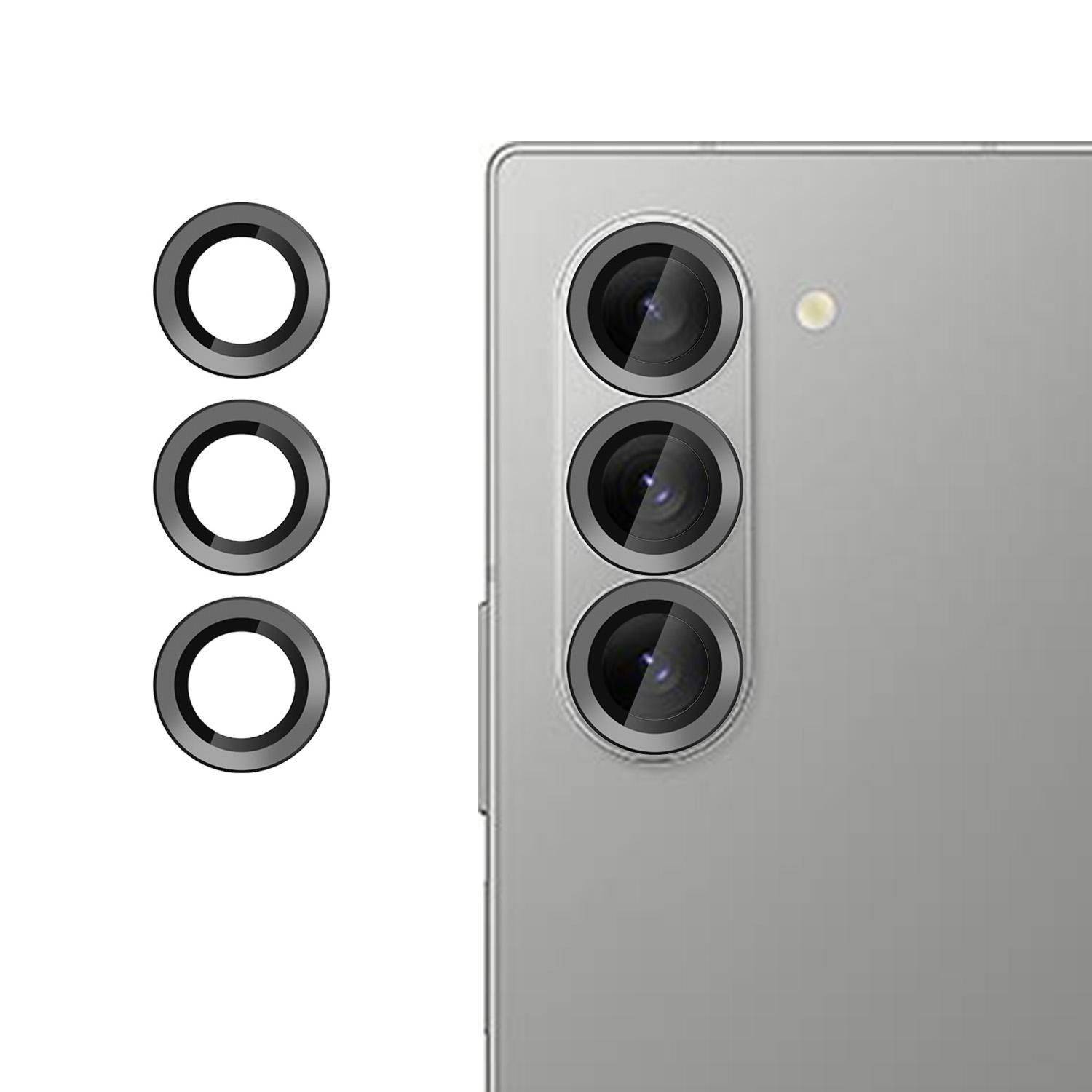 Silberner Smartphone-Rücken mit drei vertikal angeordneten hinteren Kameraobjektiven, dargestellt neben drei kreisförmigen Ringzubehören für die Kameraobjektive.