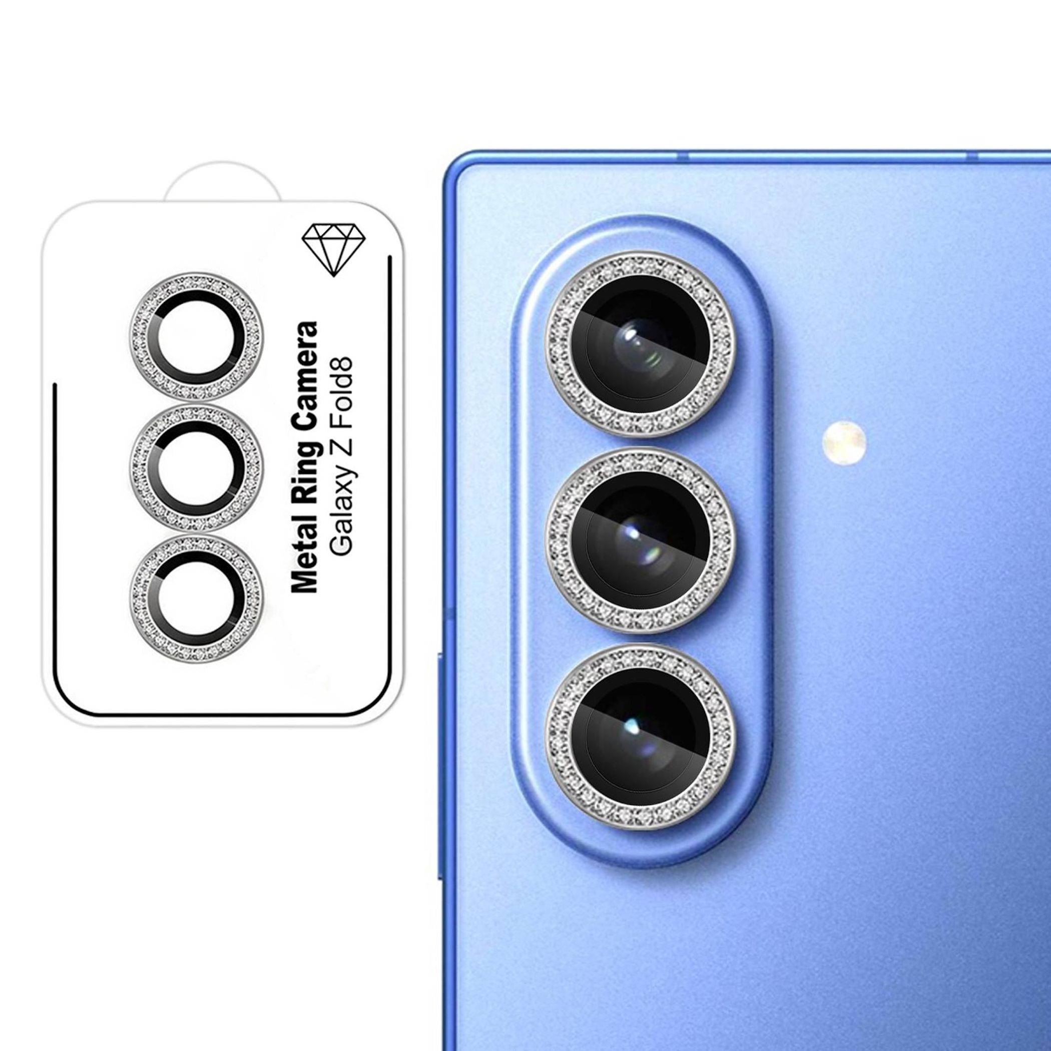 Blauer Smartphone-Rücken mit drei vertikal angeordneten Rückfahrtkameras; daneben zeigt die Verpackung „Metal Ring Camera