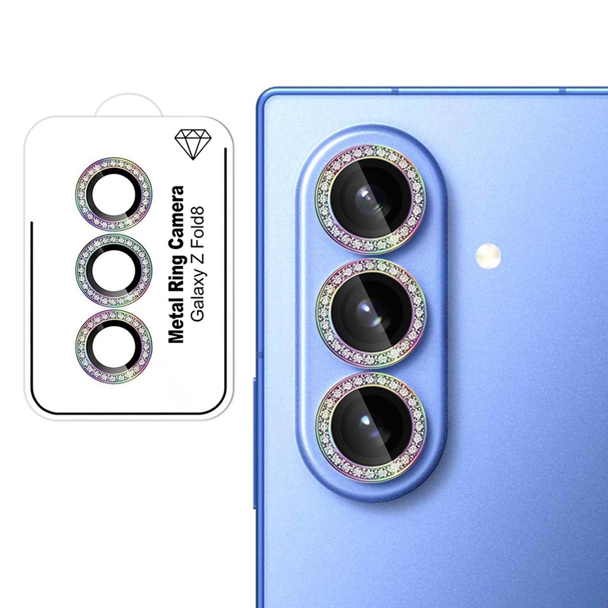 Drei juwelenbesetzte Metall-Kameraschutzringe für Galaxy Z Fold8, neben einem Telefon mit drei rückseitigen Objektiven gezeigt.