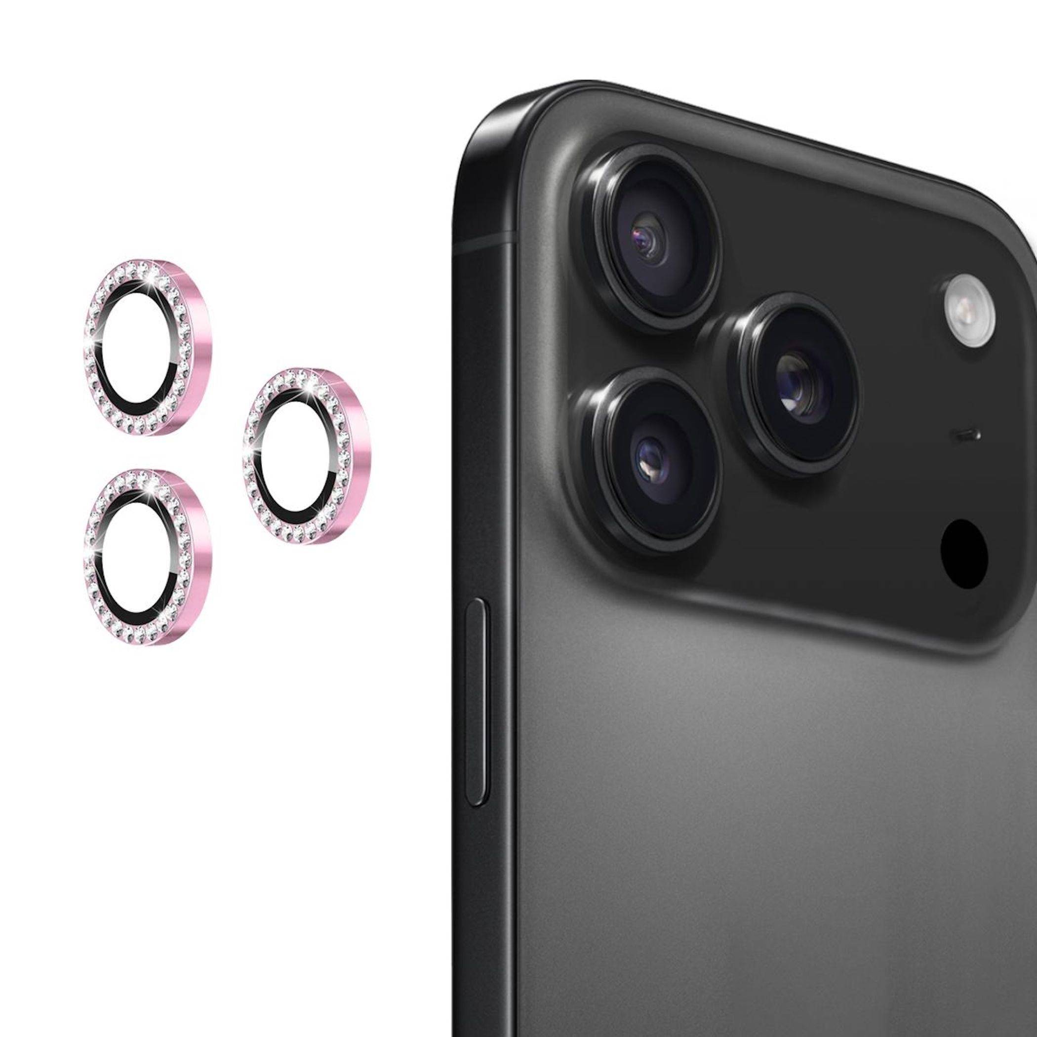 Drei rosa Schmuckstein-Kameraobjektivringe werden neben der Rückseite eines schwarzen Smartphones mit dreifachen Rückkameras gezeigt, was auf schützende dekorative Objektivabdeckungen hinweist.