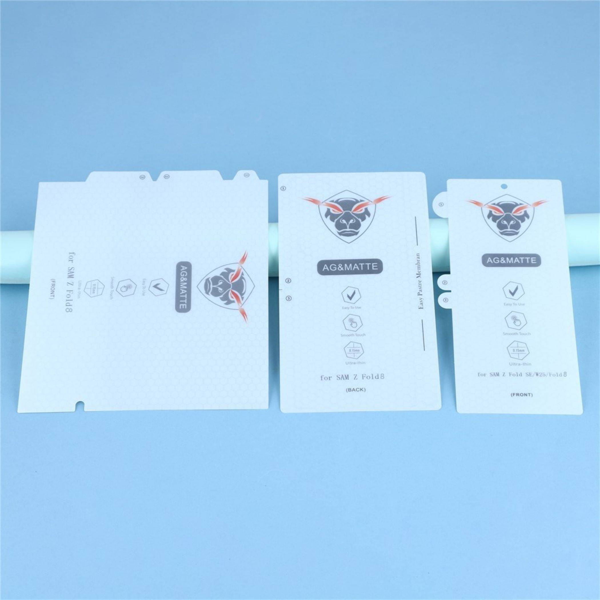 Drei weiße AG&MATTE-Verpackungseinsätze oder Beutel mit Logo und Produktsymbolen, nebeneinander auf blauem Hintergrund angeordnet.
