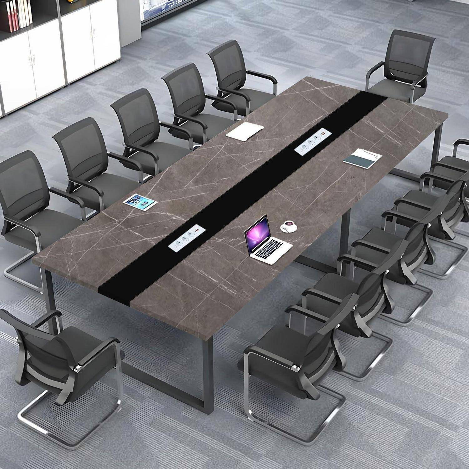 Moderner Konferenzraum mit einem großen rechteckigen Besprechungstisch, umgeben von leeren Bürostühlen, sowie einem aufgeklappten Laptop und einer Tasse in der Mitte.