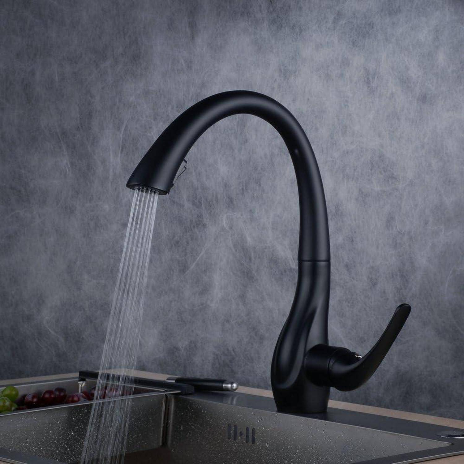Schwarzer ausziehbarer Küchenarmatur mit Wasser, das in ein Edelstahlspülbecken gegen einen grauen Spritzschutz fließt.
