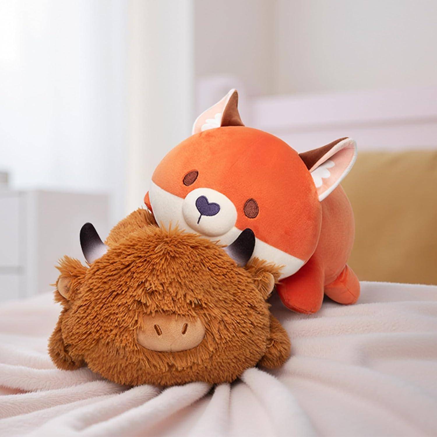 Orangefarbenes Plüschtier-Fuchs liegt auf einem flauschigen braunen Plüschtier auf einem weichen Bett oder einer weichen Decke.
