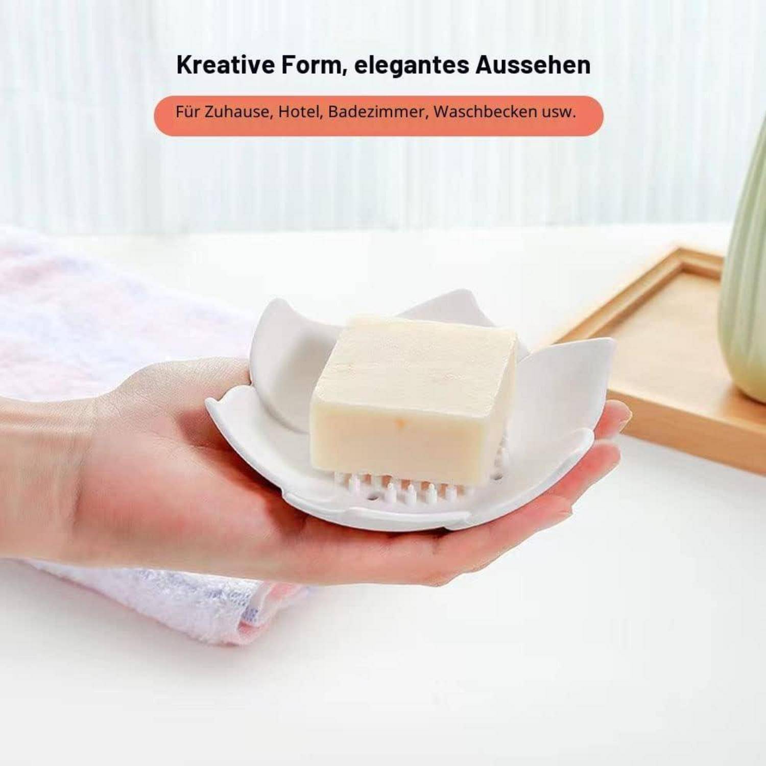 Hand hält eine weiße Seifenschale mit einem Stück Seife; deutscher Text sagt „Kreative Form, elegantes Aussehen