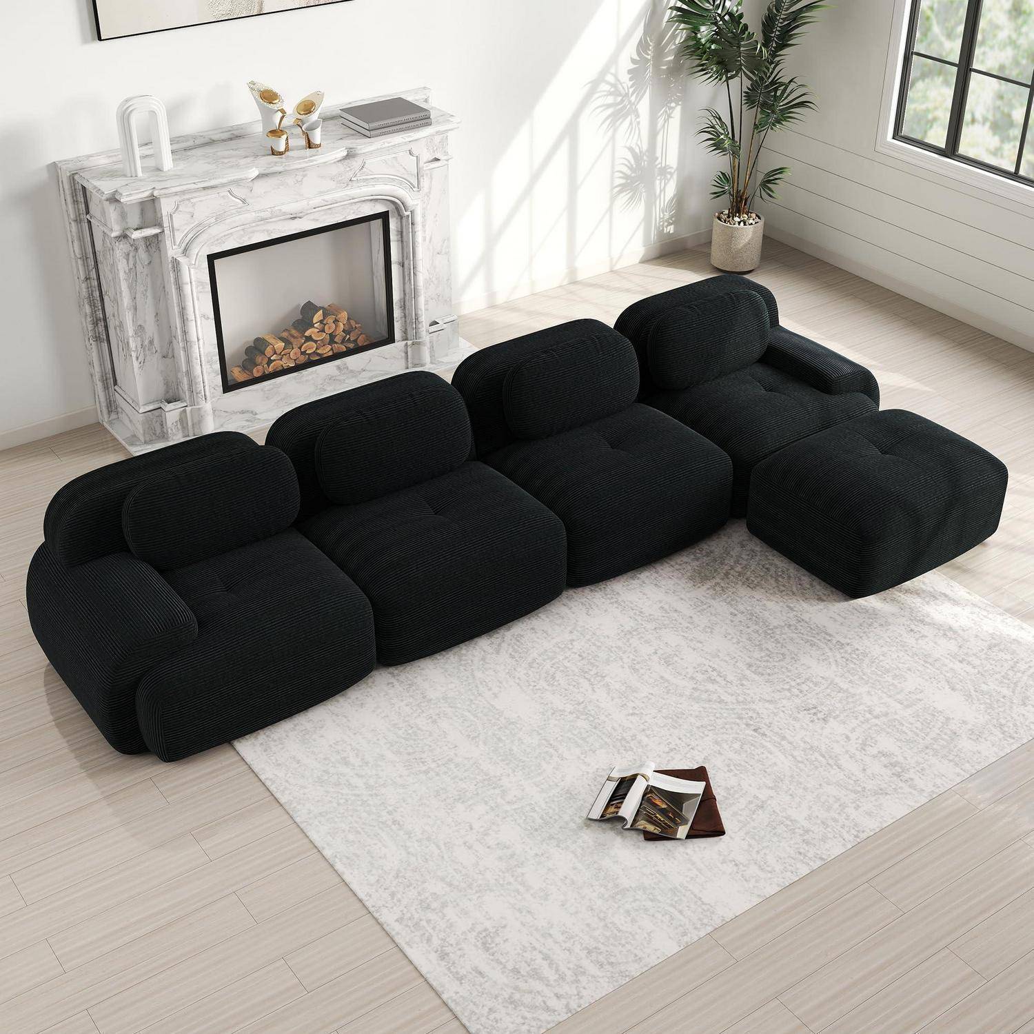 Schwarzes modulares niedriges Sofa mit gerundeten Kissen in einem hellen Wohnzimmer neben einem Marmorkamin, Teppich und einer Topfpflanze.