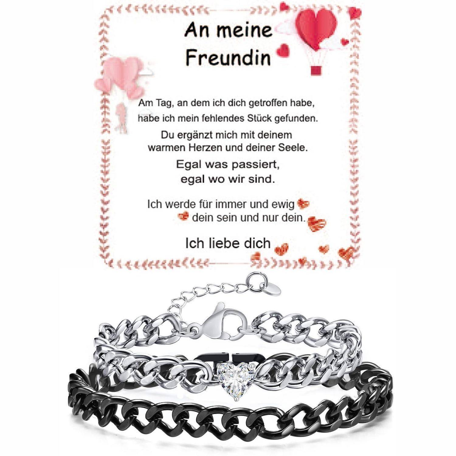 Geschenkset mit einem Liebesbrief auf Deutsch über drei ineinander verschlungenen Armbändern, einschließlich eines Herzanhängers und eines schwarzen Kettenarmbands, auf weißem Hintergrund.