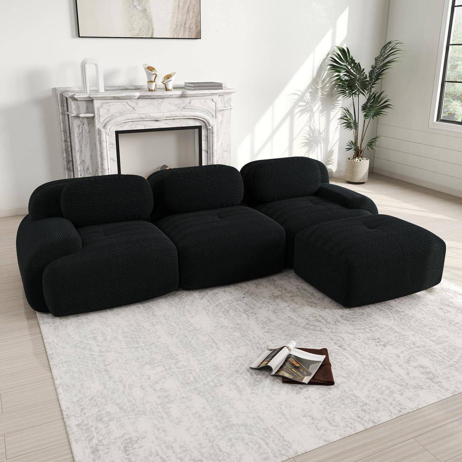 Schwarzes modulares Sofa mit abgerundeten Kissen in einem hellen minimallistischen Wohnzimmer, auf einem hellen Teppich neben einem Marmorkamin und einer Topfpflanze.