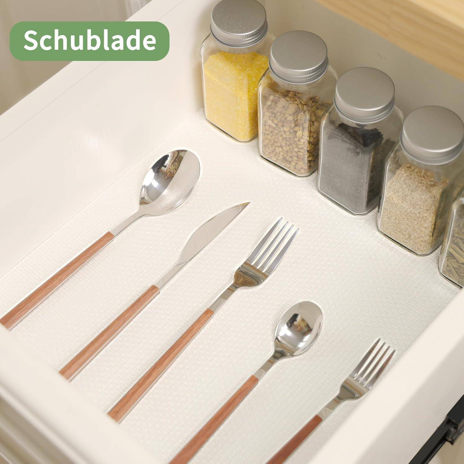 Schubladenorganizer für die Küche mit Besteck und beschrifteten Gewürzbehältern in einer weißen Schublade.