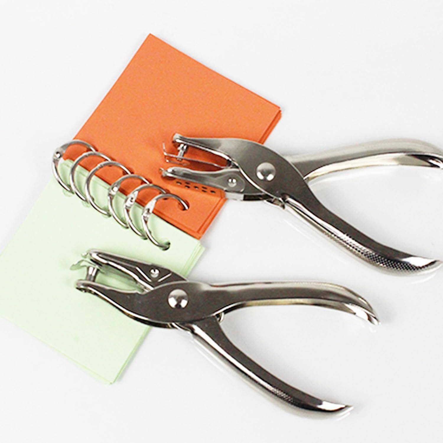 Zwei Metalllocher mit gebogenen Griffen neben einem kleinen orangefarbenen und hellgrünen Spiralnotizblock auf weißem Untergrund.