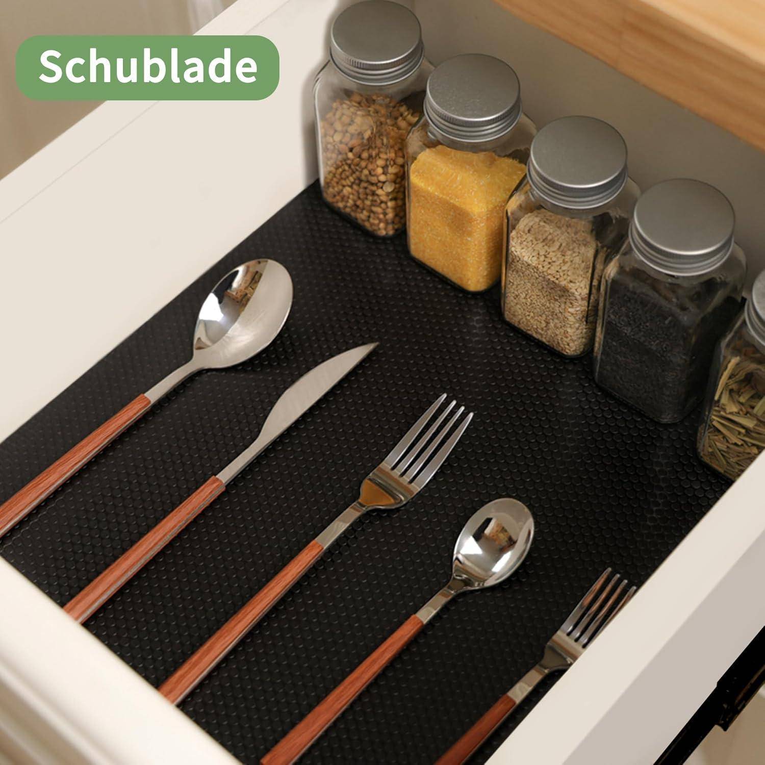 Küchenbesteck-Organizer mit schwarzer Auskleidung, silbernem Besteck und beschrifteten Gewürzdosen ordentlich angeordnet im Inneren.