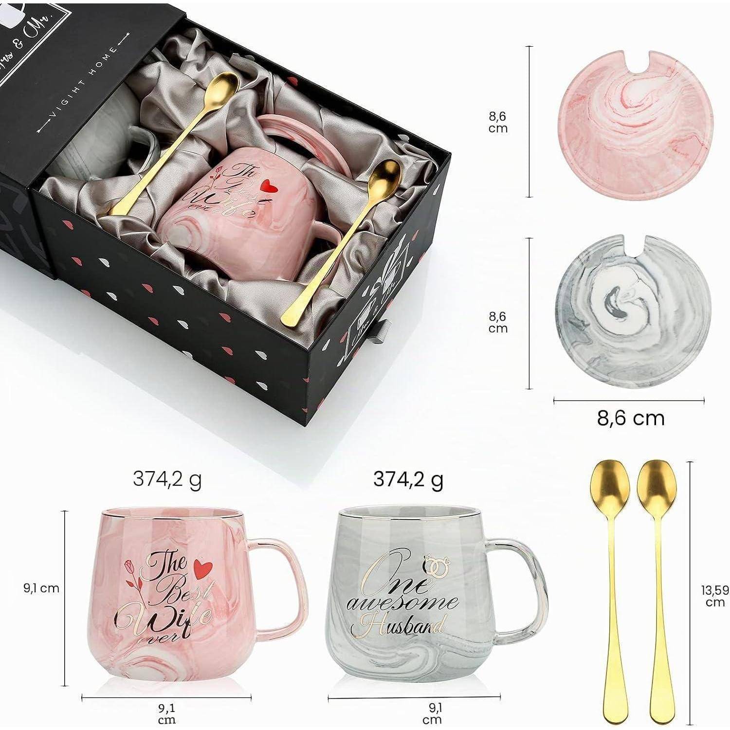 Geschenkbox mit zwei Keramiktassen und zwei goldenen Löffeln, gezeigt in rosa und grauer Wirbeldesign; Produktabmessungen sind mit 8,6 cm, 9,1 cm und 13,59 cm gekennzeichnet, Gewicht 374,2 g pro Stück.