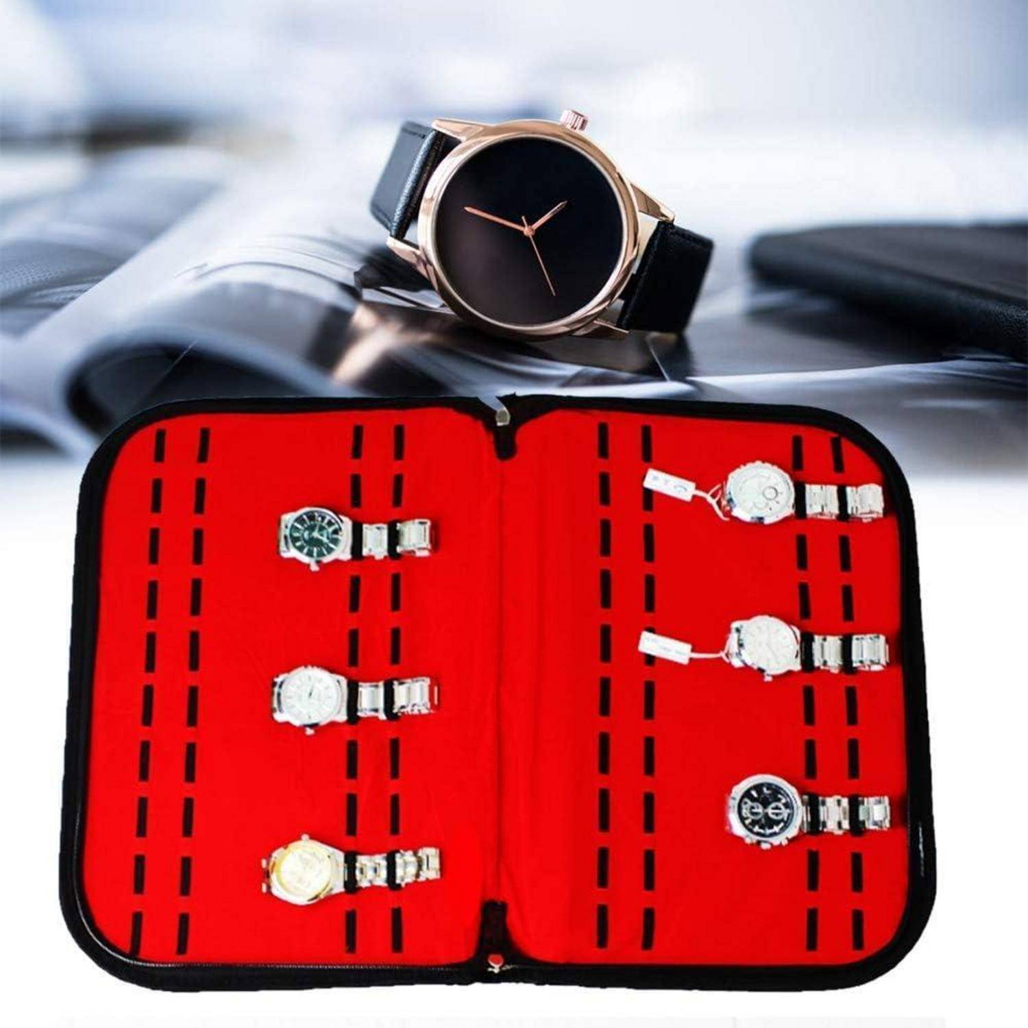 Offenes Uhrengehäuse mit fünf Armbanduhren auf rotem gefüttertem Inneren, mit einer großen Armbanduhr mit schwarzem Zifferblatt dahinter.
