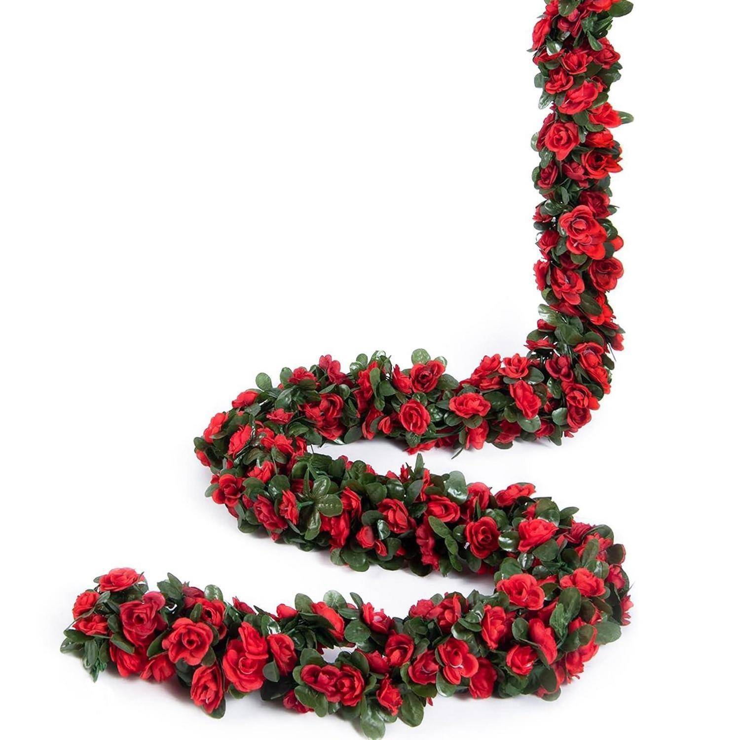 Eine aufgerollte Girlande aus roten Rosen und grünen Blättern in einer Spirale auf weißem Hintergrund angeordnet.