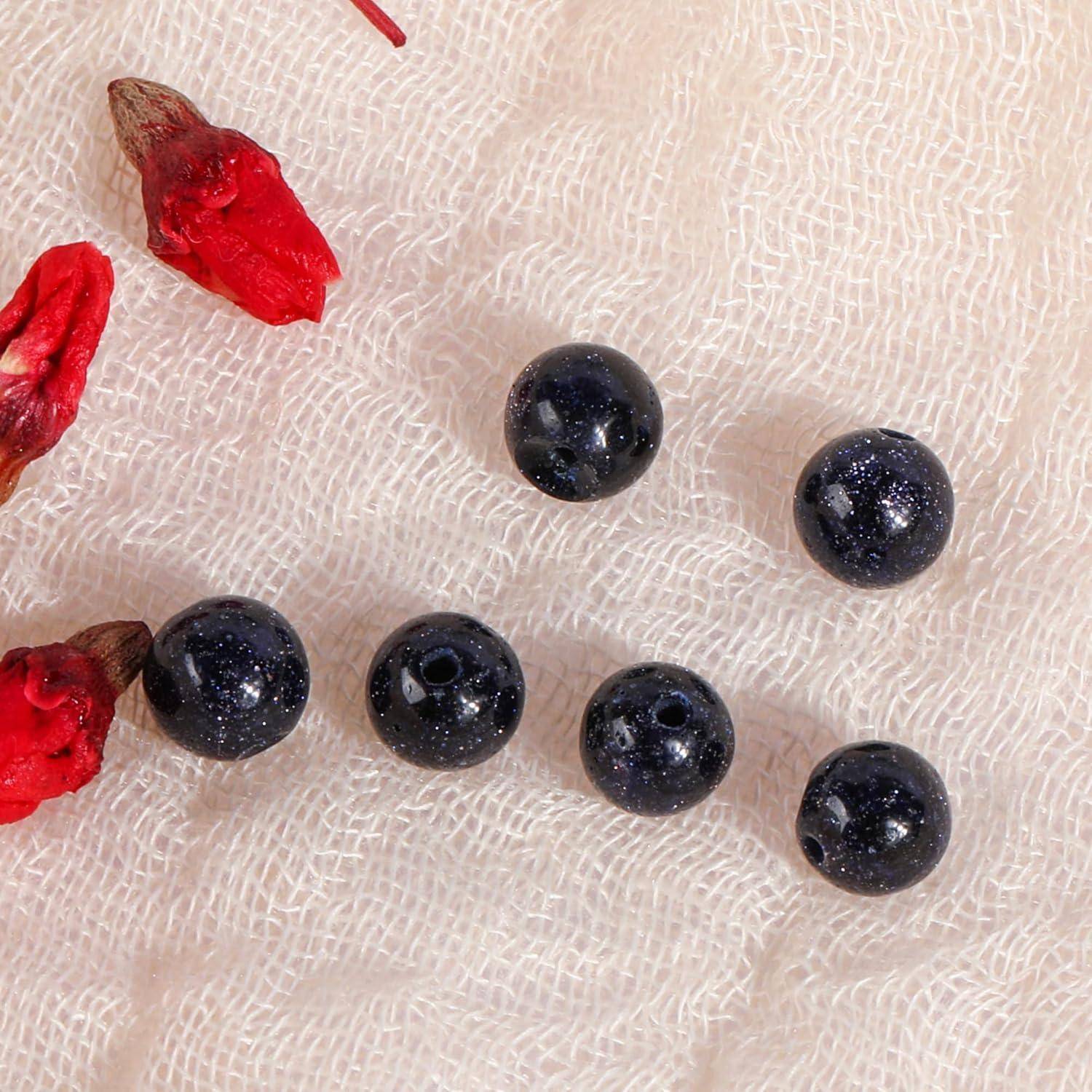 Kleine schwarze Perlen und rote Perlenbruchstücke, die auf weißem Gewebe verstreut sind.