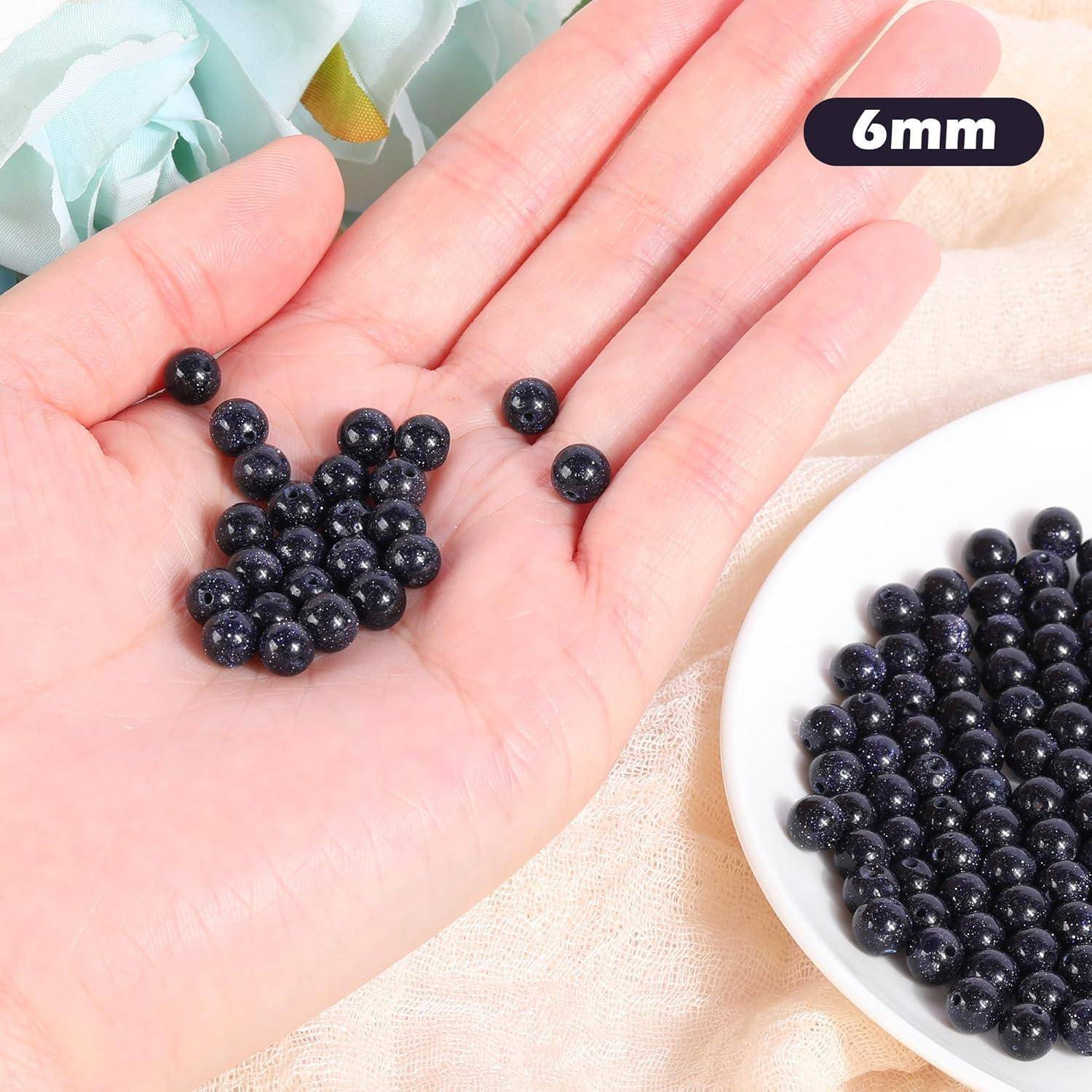 Handfläche mit vielen kleinen schwarzen Perlen, beschriftet mit „6mm