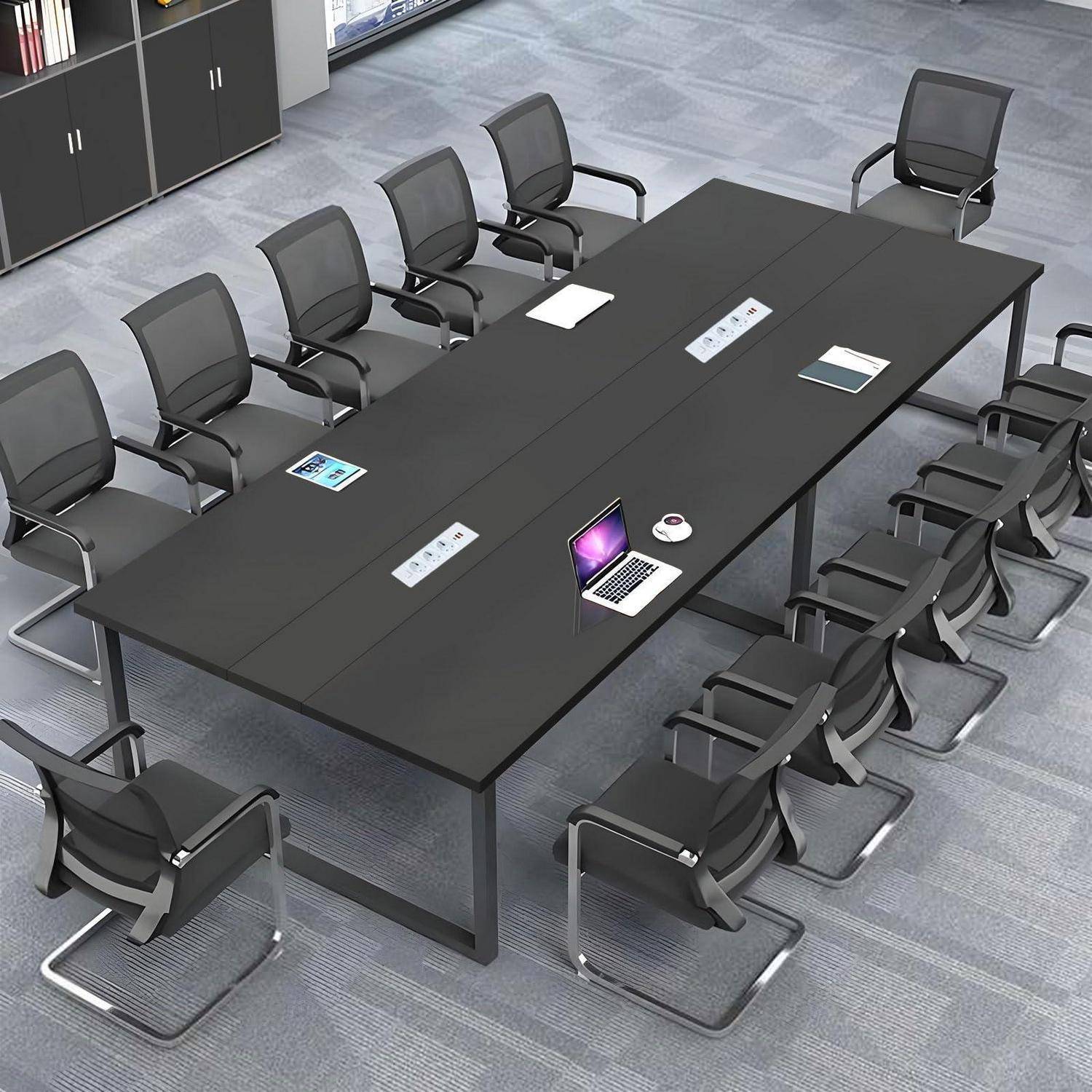 Leerer moderner Konferenzraum mit einem großen schwarzen Konferenztisch, vielen Stühlen und einigen auf dem Tisch hinterlassenen Laptops und Dokumenten.