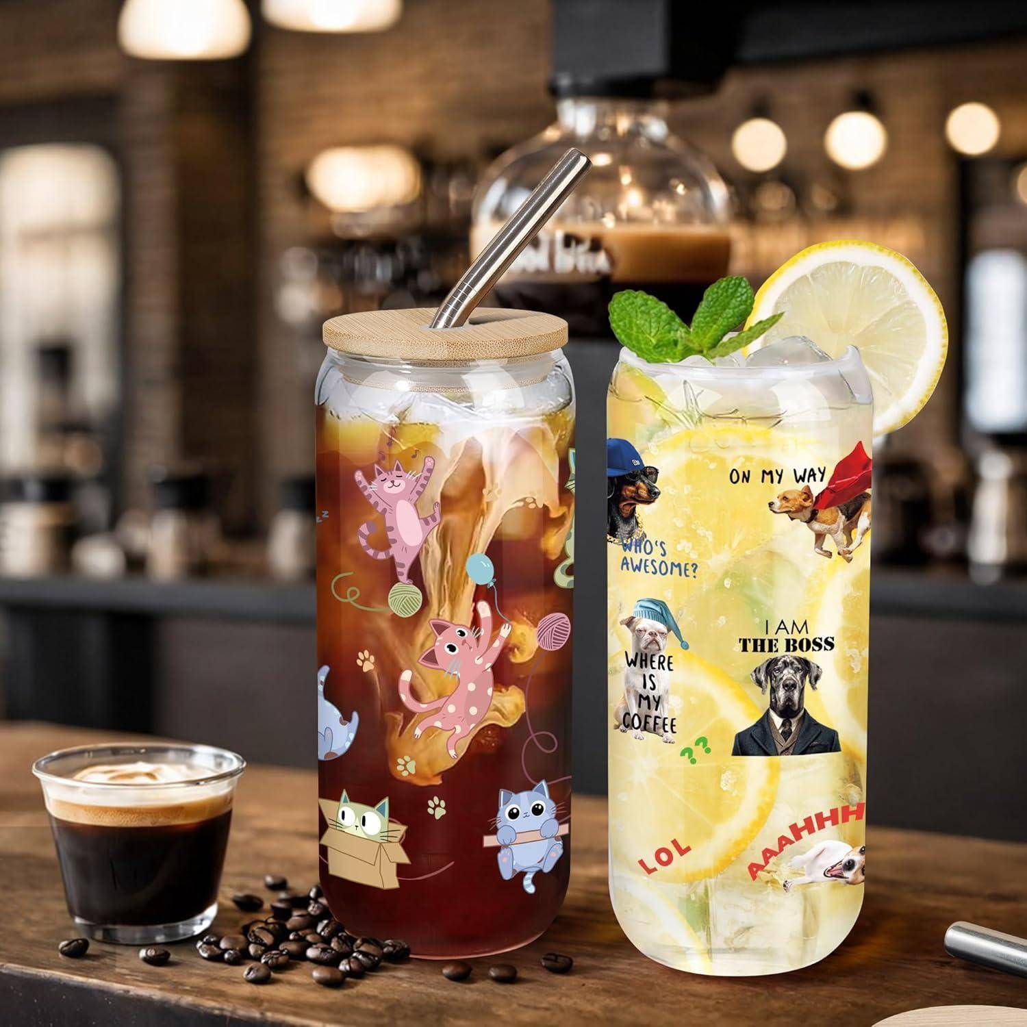Zwei eisgekühlte Getränke in verzierten Glaspokalen auf einem Café-Tresen, eines mit dunklem Kaffee mit Metallstrohhalm und eines mit Zitronengetränk mit Scheibenschmuck und Aufklebern.