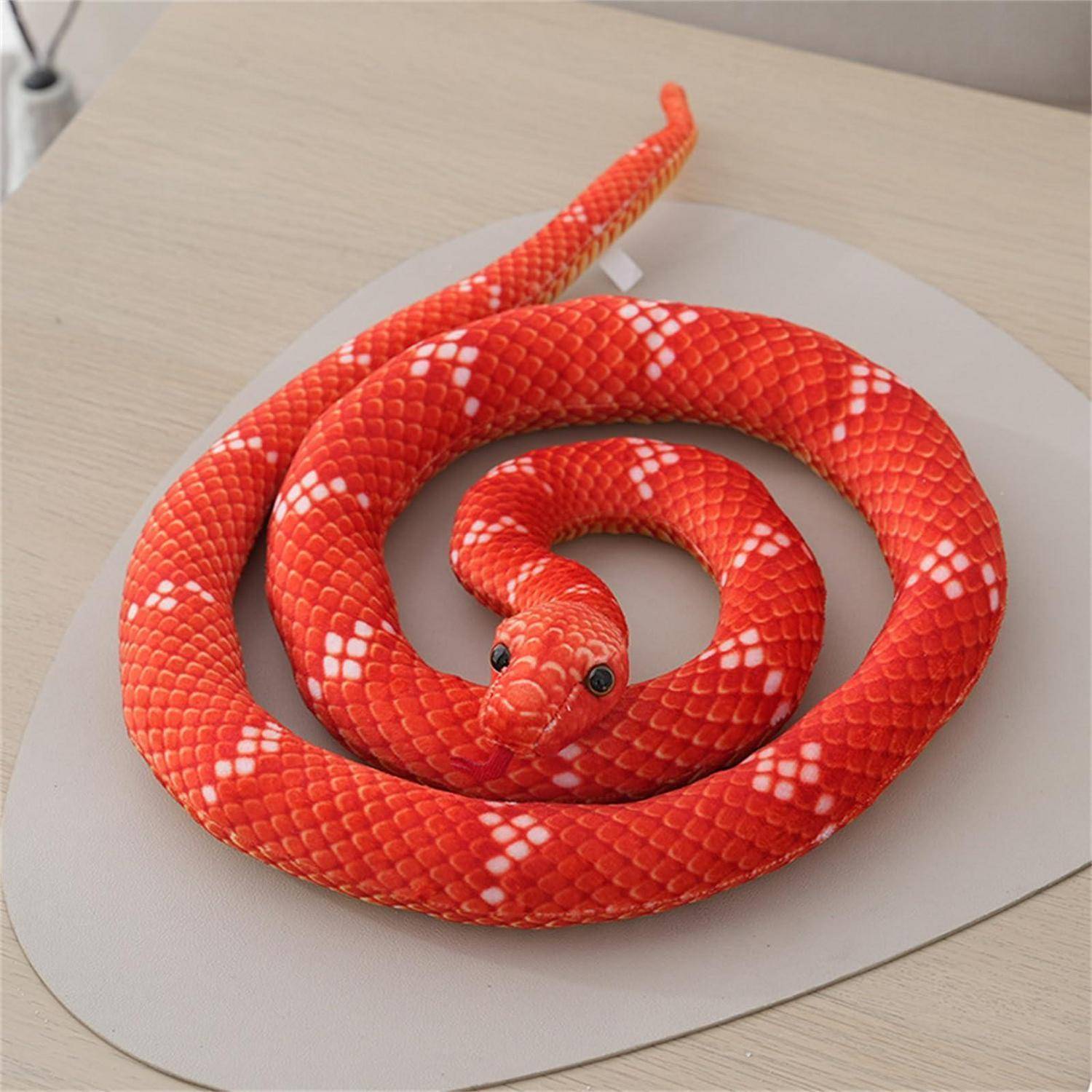 Leuchtend rote Schlange, die in einer Spirale auf einem beigefarbenen Teller oder einer beigefarbenen Matte aufgerollt ist, von oben auf einer hellen Tischplatte fotografiert.