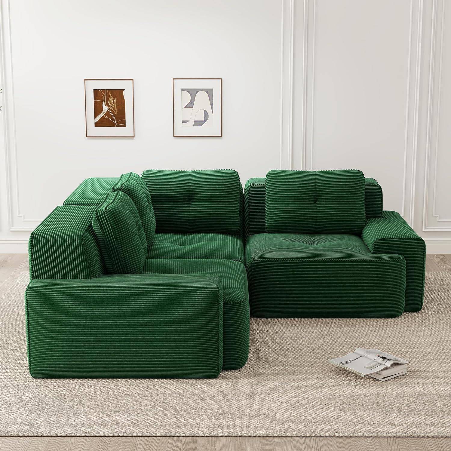 Grünes modulares Ecksofa in einem minimalistischen weißen Raum, mit zwei gerahmten abstrakten Drucken an der Wand und Zeitschriften auf dem Boden.