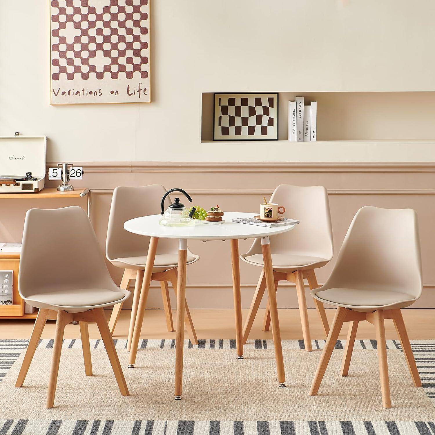 Moderner Essplatz mit vier beigen Stühlen um einen weißen runden Tisch, dekoriert mit Accessoires und Wandkunst in einem minimalistischen Raum.