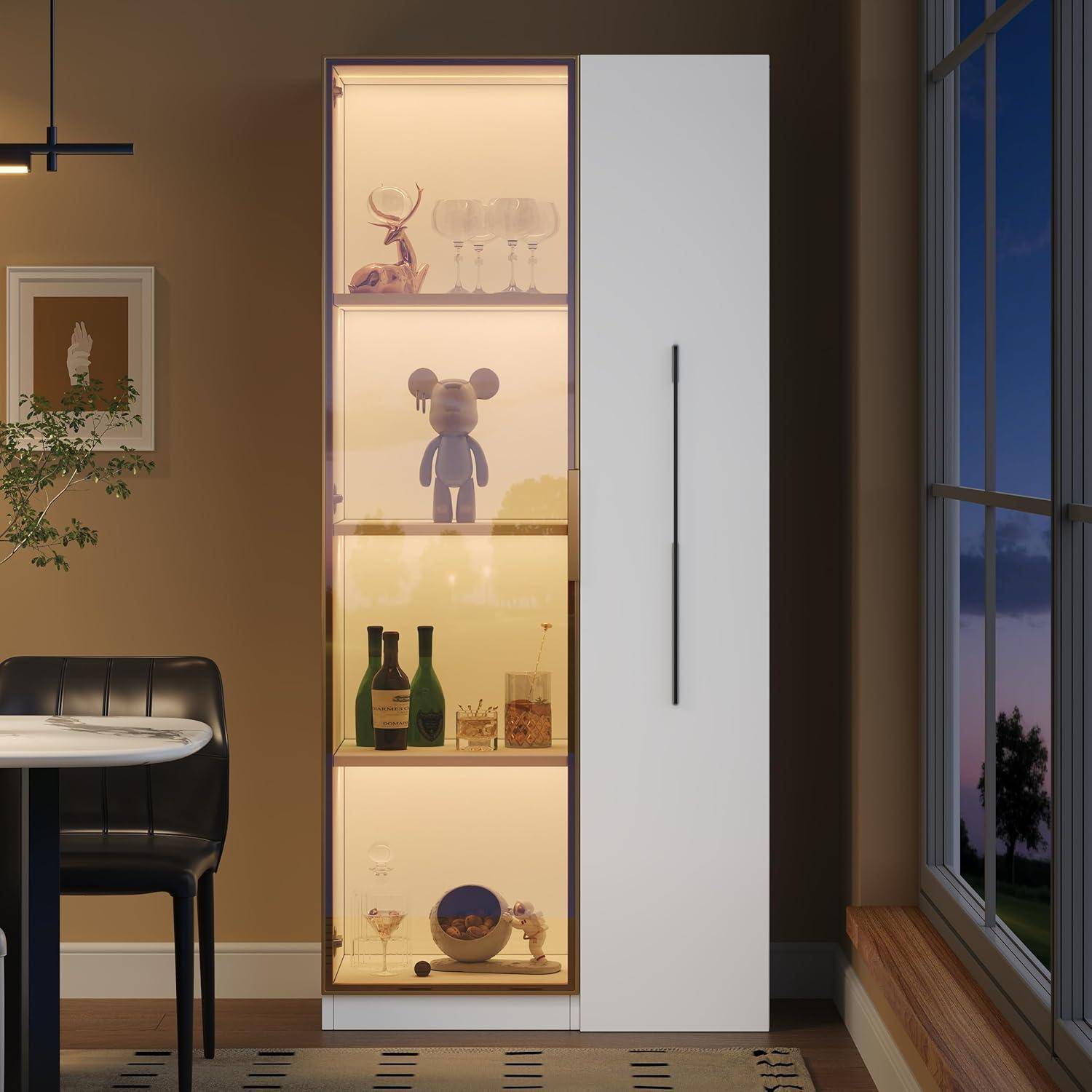 Hoher weißer Vitrinenschrank mit beleuchteten Regalen, auf denen Figuren, Glaswaren und Flaschen neben einem Fenster in der Abenddämmerung stehen.