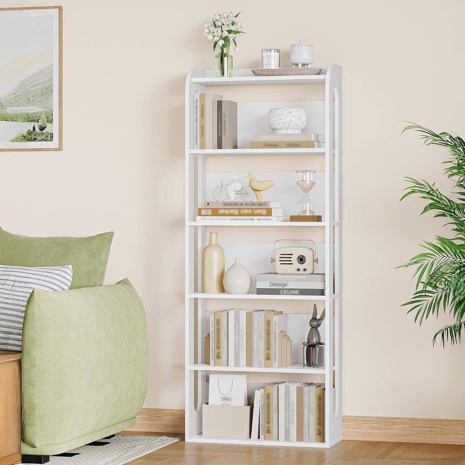 Weißes Bücherregal mit Büchern, Vasen, Blumen, einem Radio und Deko in einem hellen Wohnzimmer neben einem grünen Sofa und Wandkunst.