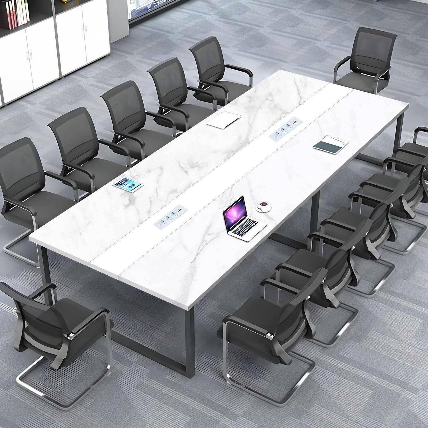 Leerer moderner Konferenzraum mit einem langen weißen Tisch, vielen schwarzen Stühlen und einem Laptop sowie Tablets auf dem Tisch.