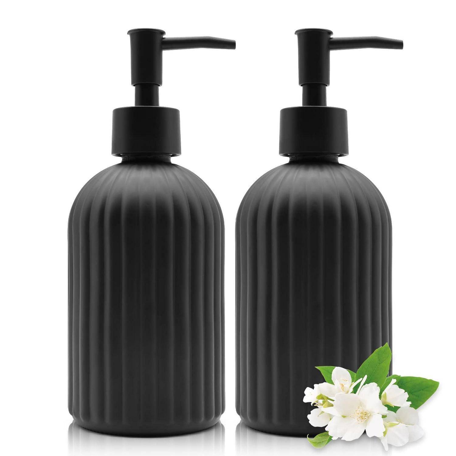 Zwei schwarze gerippte Pumpflaschen mit schwarzen Dispensern, auf weißem Hintergrund gezeigt, mit weißen Blüten und grünen Blättern vor der rechten Flasche.