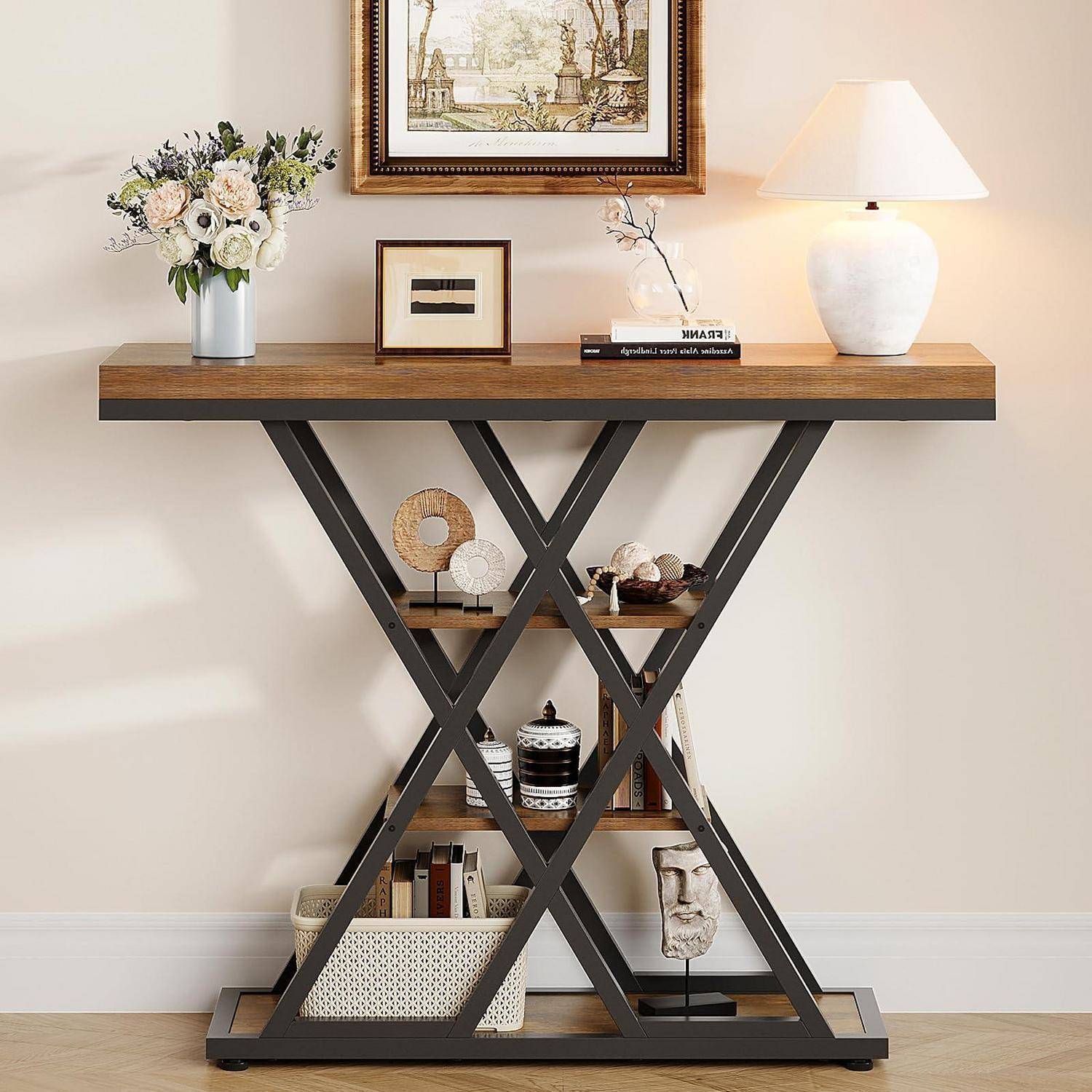 Moderner Konsolentisch mit Holzplatte und schwarzem X-Rahmen, dekoriert mit Blumen, Rahmenbildern, Lampe und kleinen Dekorationsobjekten auf Regalen.
