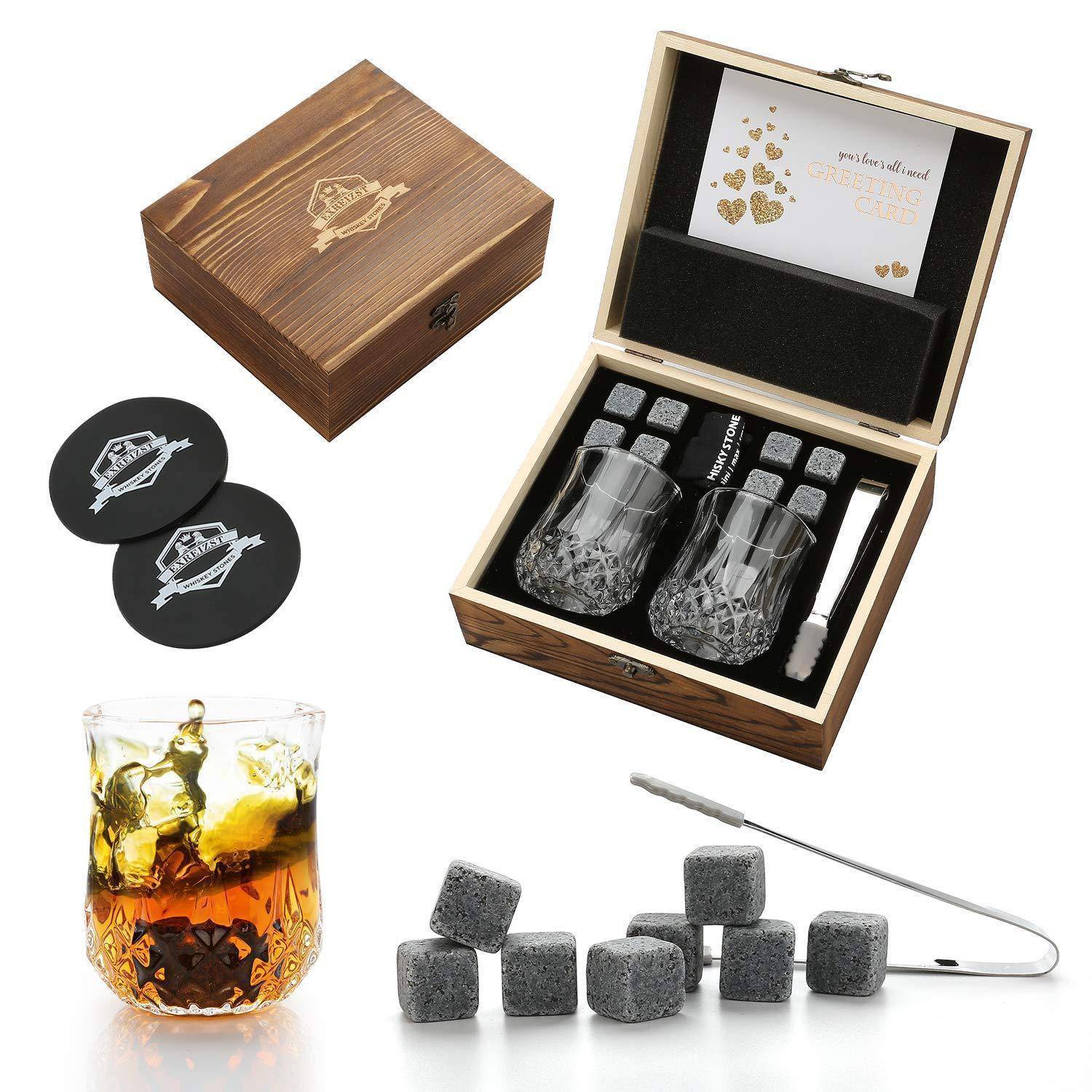Geschenkset mit gravierter Holzbox, zwei gemusterten Whiskeygläsern, vier Stein-Eiswürfeln, Untersetzer und Zange; ein Glas mit einem Getränk abgebildet.