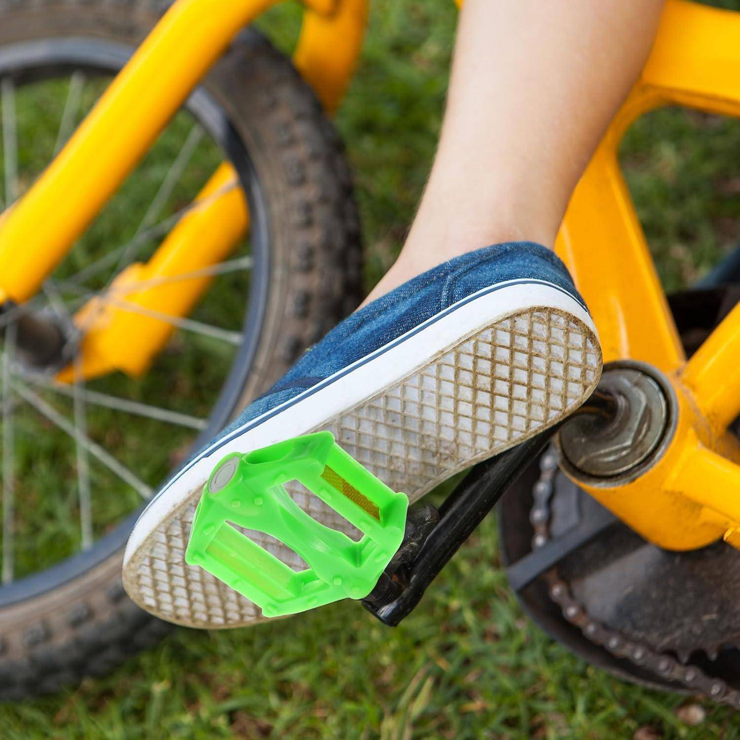 Nahaufnahme eines Fußes auf einem Fahrradpedal, in einem blauen Sneaker mit einer hellgrünen Pedalklammer auf einem gelben Fahrrad.